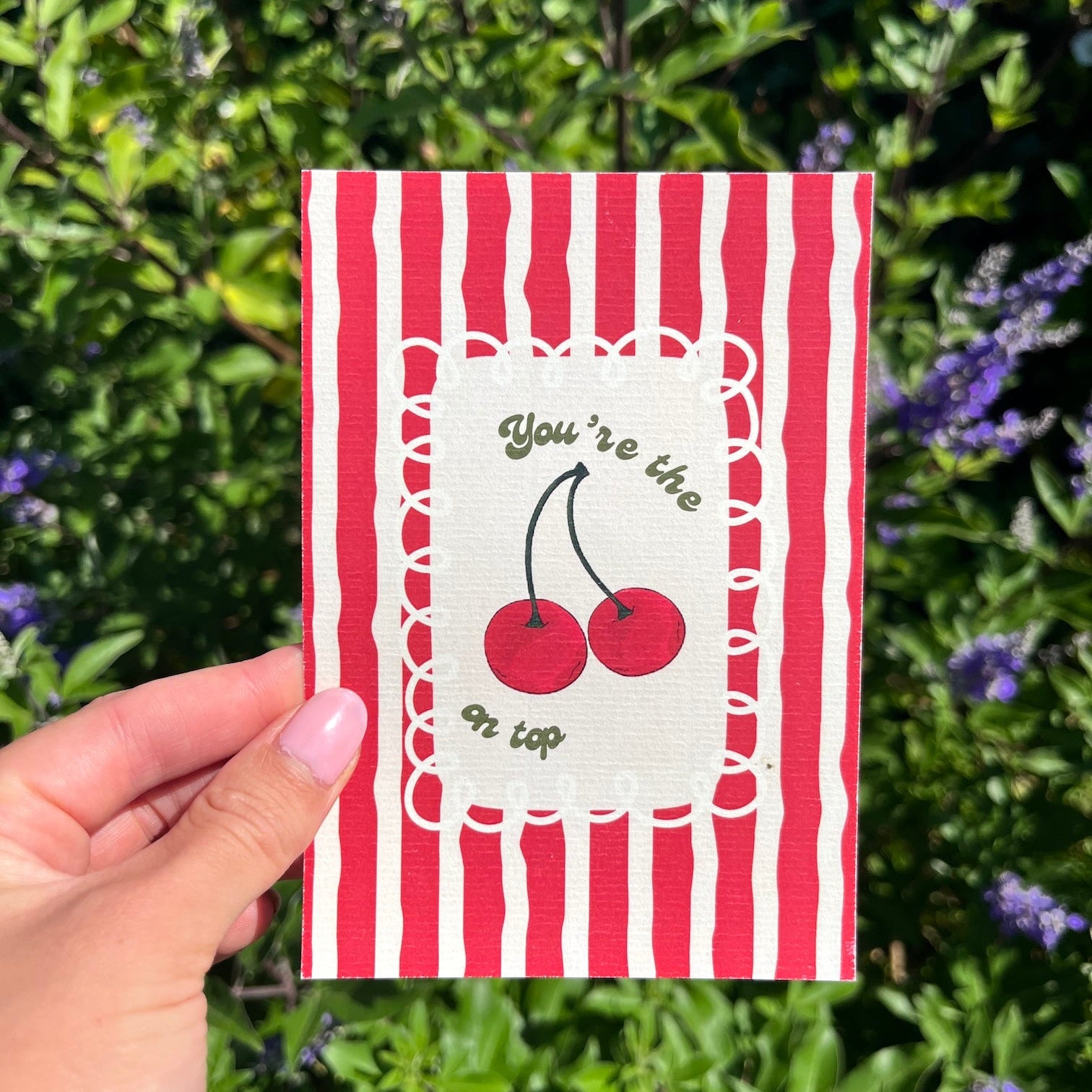 Kaart A6 formaat op linnen look papier met rood gestreepte achtergrond en kersjes met de tekst 'You're the cherry on top'.