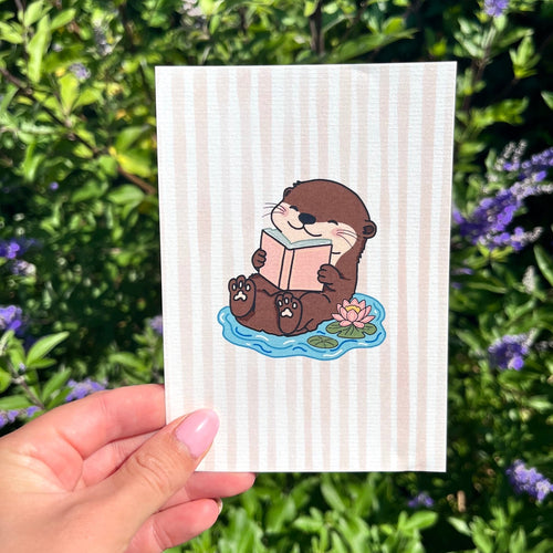 Kaart op linnen look papier met een otter in het water erop die een boek leest.