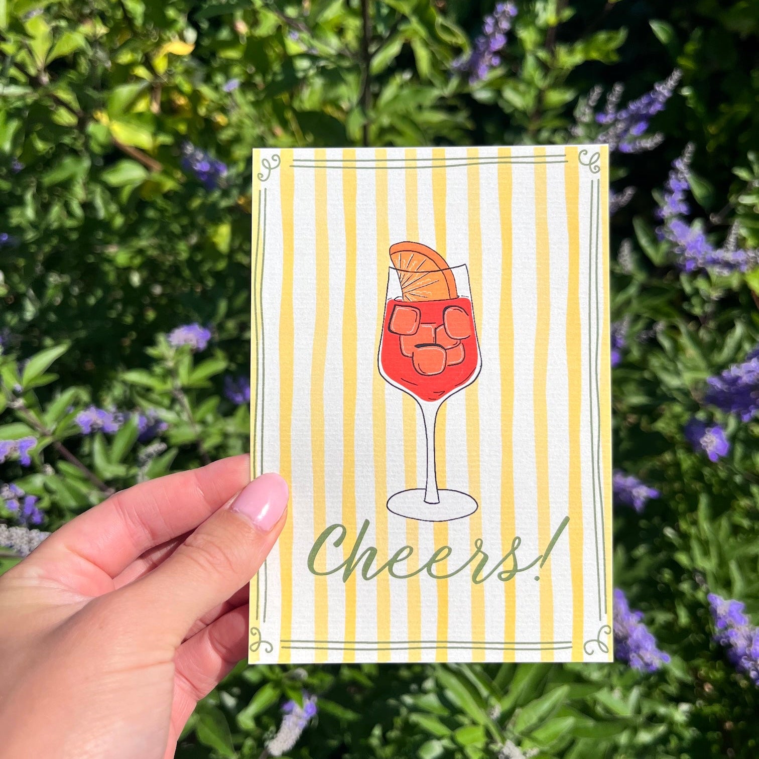 Kaart van linnen look papier met een aperol glas erop en de tekst 'Cheers!'.